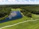 Panoramic aerial shot of a verdant golf course with a tranquil lake and surrounding lush green trees at 8924 Misty Creek Dr, Sarasota, FL 34241