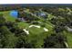 Aerial view of a lush golf course featuring a lake and sand traps surrounded by mature trees at 8924 Misty Creek Dr, Sarasota, FL 34241