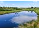 A beautiful pond surrounded by lush green grass and trees reflects the cloudy blue sky at 9012 Tequila Sunrise Dr, Sarasota, FL 34241