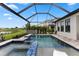 Screened-in pool with spa, rock waterfall, and views of the green common space and lake at 9012 Tequila Sunrise Dr, Sarasota, FL 34241