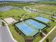 Aerial view featuring tennis and basketball courts surrounded by lush green grass and trees at 9012 Tequila Sunrise Dr, Sarasota, FL 34241