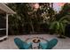 A pair of aqua chairs near a lit fire pit in an outdoor white rock backyard with lush landscaping at 9122 16Th Avenue Nw Cir, Bradenton, FL 34209
