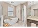 Bright bathroom features a freestanding tub, window, and a doorway leading to the shower at 9123 Raes Creek Pl, Palmetto, FL 34221