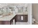 Well-lit bathroom features dual sinks with granite counters, dark wood cabinets, and tiled floors at 9123 Raes Creek Pl, Palmetto, FL 34221