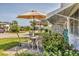 Outdoor patio with table, chairs, umbrella, and lush landscaping at 1060 Cockrill St # 1060, Venice, FL 34285