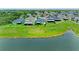Aerial view showcases homes with screened lanais on grassy lots by a serene lake at 10609 Great Cormorant Dr, Riverview, FL 33579