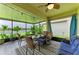 Inviting screened porch with dining set, sofa, ceiling fan, and serene lake view at 10609 Great Cormorant Dr, Riverview, FL 33579