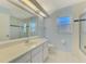 Bright bathroom featuring a long vanity with white cabinets and a glass-enclosed shower at 1144 Hoover St, Nokomis, FL 34275