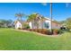 Landscaped front yard featuring mature palm trees and garden beds under a clear blue sky, enhancing curb appeal at 1144 Hoover St, Nokomis, FL 34275