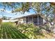 Well-maintained backyard with a screened lanai, mature tree, and grill on a small deck at 1163 Nantucket Rd, Venice, FL 34293