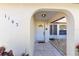 Inviting front entrance with arched doorway, tiled walkway, and a charming white front door with half-round window at 1163 Nantucket Rd, Venice, FL 34293