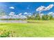 Lush backyard with a serene pond view, vibrant greenery, and clear blue skies above at 11685 Great Brook Ln, Parrish, FL 34219