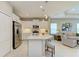 Modern kitchen with white cabinets, stainless steel appliances, and a center island with seating overlooking the living area at 11685 Great Brook Ln, Parrish, FL 34219