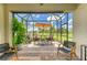 The cozy screened lanai features comfortable seating, an outdoor grill, and a serene backyard view at 11685 Great Brook Ln, Parrish, FL 34219