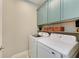 Efficient laundry room features modern appliances, overhead storage, and stylish blue upper cabinets at 11685 Great Brook Ln, Parrish, FL 34219