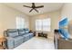 Inviting living room featuring a comfortable blue couch, a ceiling fan, and natural light from the windows at 11685 Great Brook Ln, Parrish, FL 34219