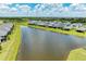 An aerial view of homes along a pond with lush landscaping and clear blue skies at 11685 Great Brook Ln, Parrish, FL 34219