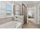 Serene bathroom with a soaking tub, a separate glass shower, and a scenic window at 12564 Night View Dr, Sarasota, FL 34238