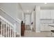 Inviting hallway with staircase, cabinet, and view into the kitchen featuring granite counters and white cabinets at 12564 Night View Dr, Sarasota, FL 34238
