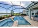 Beautiful screened-in pool and spa overlooking the water with travertine tile and outdoor kitchen at 12564 Night View Dr, Sarasota, FL 34238