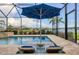 Relaxing pool area with built-in lounge chairs and blue umbrella overlooking a pond at 12564 Night View Dr, Sarasota, FL 34238