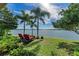 Lush backyard with lake views offers peaceful relaxation with lounge chairs and tropical palm trees at 138 Toscavilla Blvd, Nokomis, FL 34275
