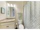 Cozy bathroom with granite countertop, framed mirror, and tub shower combo with patterned curtain at 138 Toscavilla Blvd, Nokomis, FL 34275