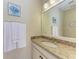 Bathroom vanity featuring granite countertops, white cabinets, decorative art, and clean white towels at 138 Toscavilla Blvd, Nokomis, FL 34275