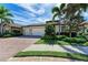 Beautiful home featuring a brick driveway, three-car garage, and lush landscaping at 138 Toscavilla Blvd, Nokomis, FL 34275