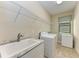 Functional laundry room with a sink, washing machine, freezer, and wire rack shelving at 138 Toscavilla Blvd, Nokomis, FL 34275