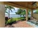 Covered brick patio features outdoor seating with views of a lush lawn and serene lake at 138 Toscavilla Blvd, Nokomis, FL 34275