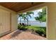 Covered brick patio features two red lounge chairs with views of a lush lawn and serene lake at 138 Toscavilla Blvd, Nokomis, FL 34275