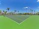 Bright and spacious tennis court with excellent lighting, ideal for recreational and competitive play, complemented by lush landscaping at 138 Toscavilla Blvd, Nokomis, FL 34275
