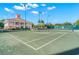 An outdoor tennis court with well-maintained surface and net, adjacent to a beautiful clubhouse with manicured grounds at 140 Sugar Mill Dr, Osprey, FL 34229