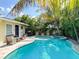 The backyard features a sparkling pool, hot tub, grill, and lounge seating amidst tropical foliage at 152 Coolidge Dr, Sarasota, FL 34236