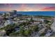 Sunset view of a charming coastal town, featuring beachfront condos, lush greenery, and the ocean at 160 Coolidge Dr, Sarasota, FL 34236