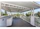 Outdoor covered balcony featuring weathered wood decking with a white ceiling, ceiling fan, and beautiful neighborhood views at 160 Coolidge Dr, Sarasota, FL 34236
