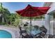 Outdoor dining table with a red umbrella and stainless steel grill next to the pool at 160 Coolidge Dr, Sarasota, FL 34236