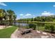 Backyard oasis with a lake view, featuring lush landscaping and a peaceful seating area at 16531 Kendleshire Ter, Lakewood Ranch, FL 34202