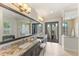 A bright bathroom with dual sinks, large mirror, a glass shower, and natural lighting at 16531 Kendleshire Ter, Lakewood Ranch, FL 34202