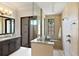 A modern bathroom with tiled walk-in shower, a vanity with dark wood cabinets, and a window for natural light at 16531 Kendleshire Ter, Lakewood Ranch, FL 34202