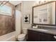Bathroom featuring a shower-tub combo, stone-look wall tiles, and vanity at 16531 Kendleshire Ter, Lakewood Ranch, FL 34202