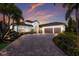 Beautiful home with tile roof, lush landscaping, and brick driveway, at dusk at 16531 Kendleshire Ter, Lakewood Ranch, FL 34202