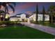 Elegant home featuring lush landscaping, brick driveway, arched entryway and sunset at 16531 Kendleshire Ter, Lakewood Ranch, FL 34202