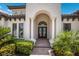 An arched front door with sidelights and manicured landscaping create an inviting entry at 16531 Kendleshire Ter, Lakewood Ranch, FL 34202