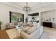 A bright living room features a chandelier, tile floors, and sliding doors to a covered lanai at 16531 Kendleshire Ter, Lakewood Ranch, FL 34202