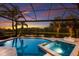 A luxurious pool and spa overlook a serene lake, framed by a screened enclosure and palm trees at 16531 Kendleshire Ter, Lakewood Ranch, FL 34202