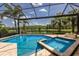 A luxurious pool and spa overlook a serene lake, framed by a screened enclosure and palm trees at 16531 Kendleshire Ter, Lakewood Ranch, FL 34202