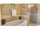 Bathroom featuring a soaking tub with a tiled surround and a separate glass-enclosed shower at 1771 Ringling Blvd # 1206, Sarasota, FL 34236