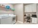 Functional laundry room with washer, dryer, desk area, and built-in storage cabinets at 1771 Ringling Blvd # 1206, Sarasota, FL 34236